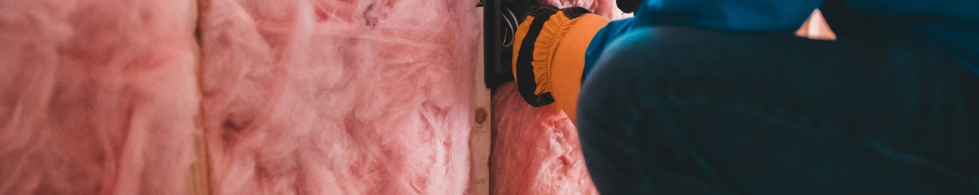 A photo of insulation being places inside a building. 