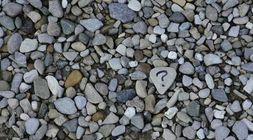 A photo with many small stones, one having a question mark on it