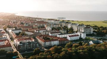 Photo of Malmo from above. looks green, with tall apartments and ocean in the background