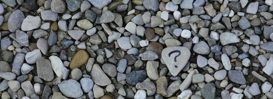 A photo with many small stones, one having a question mark on it